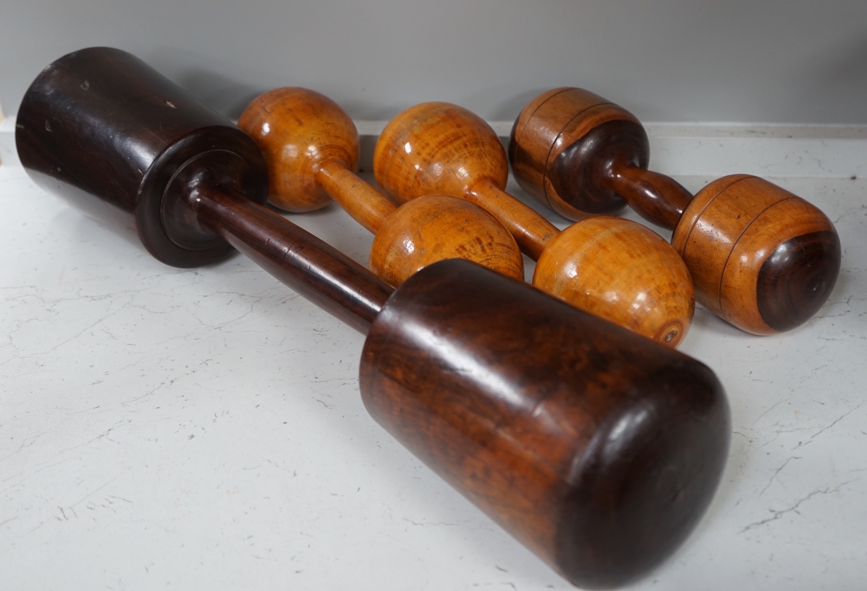 A large treen dumbbell / press together with three wooden American dumbbells by A.G. Spaulding & Bros